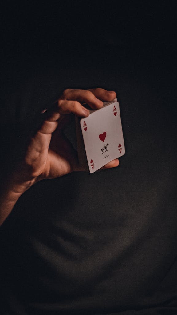 A mysterious atmospheric close-up of a hand holding the Ace of Hearts card.